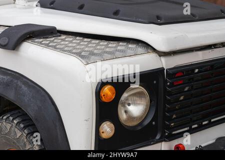 Side, Türkei -20. Februar 2022: Weißer Land Rover Defender , Nahaufnahme der Autoscheinwerfer. Nahaufnahme von außen. Stockfoto