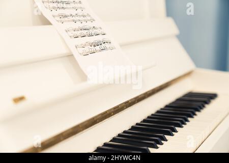 Weißes Klavier und Notenblatt mit selektivem Fokus auf klassischer Musik. Hochwertige Fotos Stockfoto