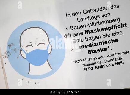 Stuttgart, Deutschland. 15. März 2022. An der Eingangstür zu einem Verwaltungsgebäude hängt ein Schild, das Menschen zum Tragen von Schutzmasken anweist. Aufgrund der hohen Infektionszahlen will Baden-Württemberg die Corona-Regeln am 20. März nicht vollständig auslaufen lassen. (To dpa: 'Baden-Württemberg hält sich an das obligatorische Tragen von Masken in Innenräumen') Quelle: Bernd Weißbrod/dpa/Alamy Live News Stockfoto