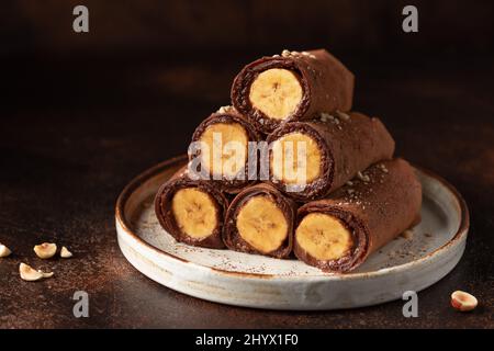 Mit Bananen gefüllte Schokoladencrepes auf dunklem Hintergrund Stockfoto