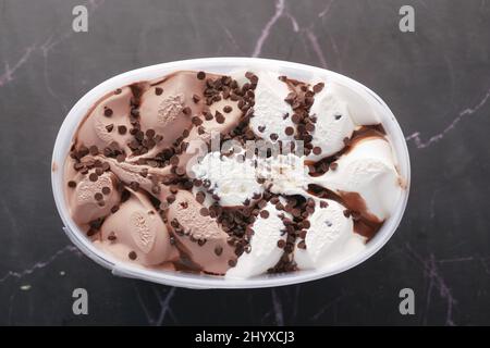 Schokoladeneis in einem Kunststoffbehälter auf Schwarz Stockfoto