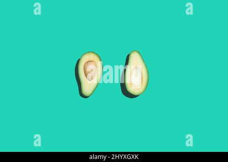 Minimale Draufsicht auf Avocadohälfte auf kontrastfarbenem neonblauem Hintergrund, gesunde Ernährung und veganes Konzept, Kopierraum Stockfoto