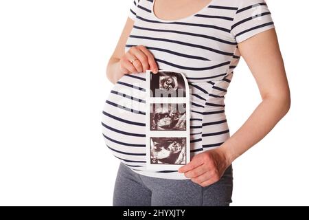 Eine Schwangerin steht und hält ihren Ultraschall-Baby-Scan Stockfoto