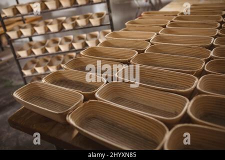 Blick aus der Perspektive auf Korbbrotkörbe, die auf dem Tisch und im Regal in der Bäckerei angeordnet sind Stockfoto