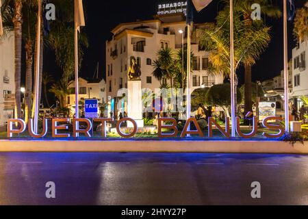 Nachtaufnahmen in luxuriöser und berühmter Lage von Marbella - Puerto Banus Bay. Blick auf das Schild Puerto Banus, auf der Avenida Julio Iglesias Stockfoto