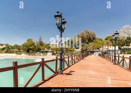 Blick auf die rote Holzbrücke 'Embarcadero' in Marbella. Blick auf das Luxusgebiet Puente Romano, teure Urbanisationen. Berg „La Concha“. Stockfoto