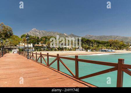 Blick auf die rote Holzbrücke 'Embarcadero' in Marbella. Blick auf das Luxusgebiet Puente Romano, teure Urbanisationen. Berg „La Concha“. Stockfoto