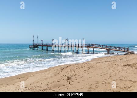 Blick auf die rote Holzbrücke 'Embarcadero' in Marbella. Blick auf das Luxusgebiet Puente Romano, teure Urbanisationen. Berg „La Concha“. Stockfoto