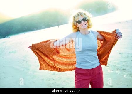 Junge reife blonde kaukasische Frau an einem sonnigen Tag draußen an einem Strand. Berria Beach, Kantabrien, Spanien, Europa. Stockfoto