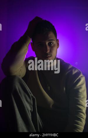 Junger Mann aus dem Nahen Osten aus Serbien posiert vor einem lila Licht Stockfoto