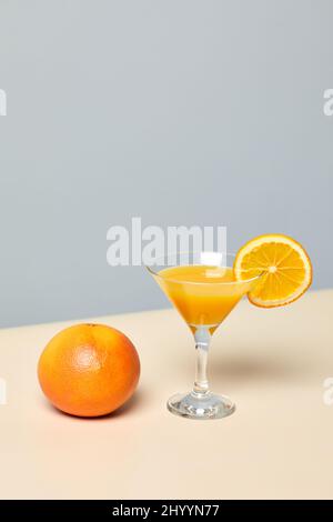 Minimaler Schuss frischen Orangensaft in Cocktailglas vor pastellfarbenem Hintergrund, gesunder Lebensstil und Diät-Konzept Stockfoto