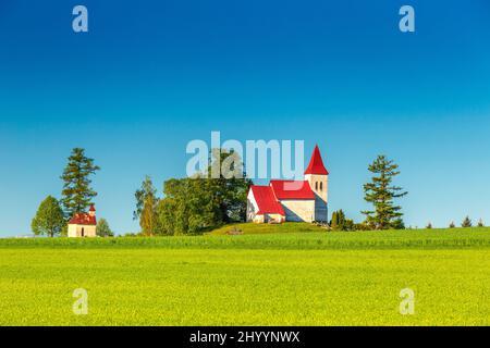 Ländliche Landschaft mit einer Kirche im Hintergrund. Kirche des heiligen Kosmas in Abramova, Region Turiec, Slowakei, Europa. Stockfoto