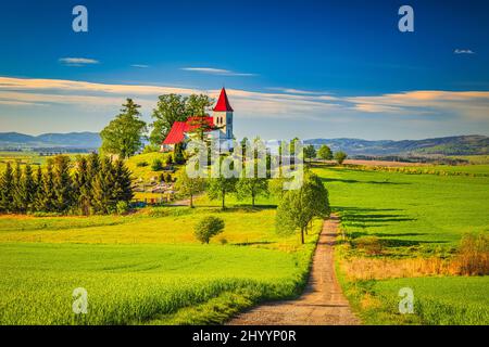 Ländliche Landschaft mit einer Kirche im Hintergrund. Kirche des heiligen Kosmas in Abramova, Region Turiec, Slowakei, Europa. Stockfoto