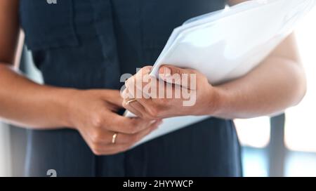 Für ihren anstrengenden Tag vor uns organisiert zu bleiben. Nahaufnahmen einer nicht erkennbaren Geschäftsfrau, die Papierkram in einem Büro hält. Stockfoto