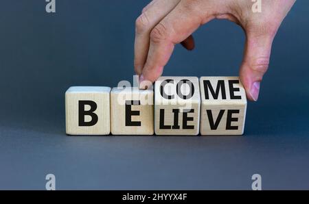 Symbol werden oder glauben. Geschäftsmann dreht Holzwürfel und ändert das Konzept Wort glauben zu werden. Schöne graue Tabelle grauen Hintergrund. Unternehmen Stockfoto