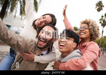 Fröhliche junge Freunde aus verschiedenen Kulturen und Rassen, die Selfie im Freien machen. Fröhliche Paare, die zusammen Spaß haben Stockfoto