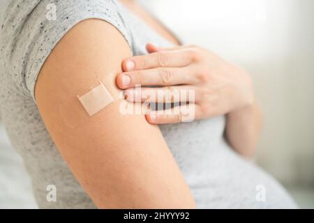 Impfung einer Schwangeren. Nahansicht der Schulter nach der Impfstoffinjektion mit Klebeband. Covid-Impfkonzept. Gesundheit und Medizin während der Schwangerschaft. Stockfoto