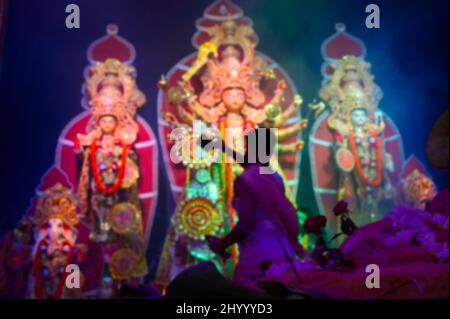 Das verschwommene Bild der Göttin Durga wird von einem hinduistischen Priester mit Spiegel verehrt. VOG, die heilige Speise wird Durga angeboten. Größtes Festival von Hind Stockfoto