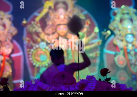 Das verschwommene Bild der Göttin Durga wird von einem hinduistischen Priester mit Chamor verehrt. VOG, die heilige Speise wird Durga angeboten. Größtes Festival von Hind Stockfoto