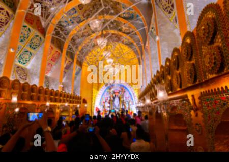 Verschwommenes Bild von Kalkutta, Westbengalen, Indien. Hinduistische Anhänger besuchen dekoriertes Durga Puja-Pandal in der Nacht mit Idol der Göttin Durga im Inneren. Stockfoto