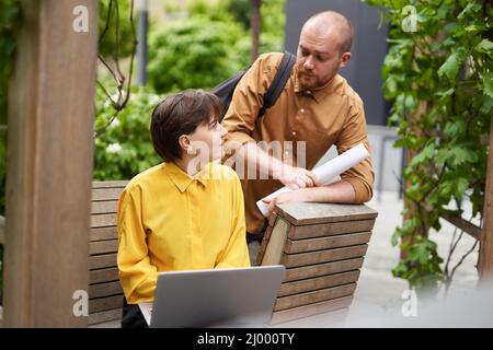 Finanz- und Immobilienkonzept. Mann und Frau Geschäftspartner diskutieren Projekt im Freien im Park mit Laptop. Treffen von Kollegen, die im Sommer über Arbeit im Freien sprechen. Hochwertige Bilder Stockfoto