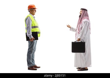 Reifer männlicher Bauingenieur und ein saudi-arabischer Geschäftsmann, der auf blauem Hintergrund ein isoliertes Gespräch führt Stockfoto