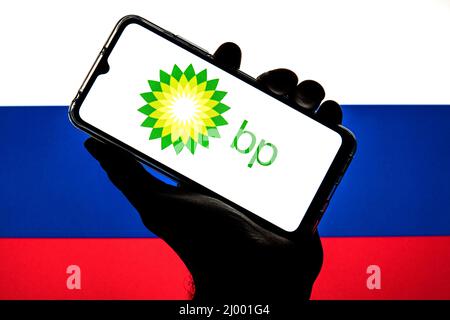 In dieser Abbildung ist ein Logo von BP plc zu sehen, das auf einem Smartphone mit einer Flagge der Russischen Föderation im Hintergrund angezeigt wird. Stockfoto