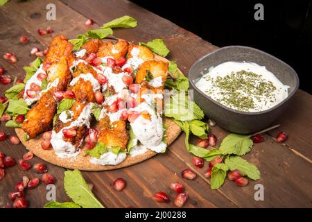 Halloumi-Käse gebratenen mit Minze Dekor, Granatapfel und spezielle Minze und Joghurt-Sauce isoliert auf einem alten rustikalen Holztisch Hintergrund Stockfoto