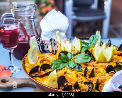 Nahaufnahme von hausgemachten Paella, traditionellen und spezifischen Speisen aus Spanien. Dekoriert mit Garnelen, Muscheln, Calamari, Zitrone und Basilikum. Traditionelle Sp Stockfoto