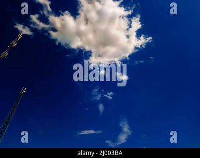 Zwei Antennen, Türme eines Mobilfunkanbieters gegen einen blauen Himmel. Blauer Himmel mit schönen weißen Wolken. Antennen für die mobile Kommunikation, für mobiles Phon Stockfoto