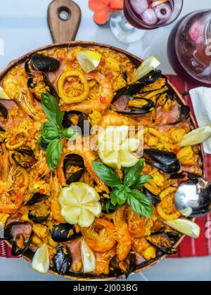 Nahaufnahme von hausgemachten Paella, traditionellen und spezifischen Speisen aus Spanien. Dekoriert mit Garnelen, Muscheln, Calamari, Zitrone und Basilikum. Traditionelle Sp Stockfoto