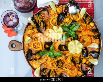 Nahaufnahme von hausgemachten Paella, traditionellen und spezifischen Speisen aus Spanien. Dekoriert mit Garnelen, Muscheln, Calamari, Zitrone und Basilikum. Traditionelle Sp Stockfoto