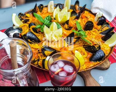 Nahaufnahme von hausgemachten Paella, traditionellen und spezifischen Speisen aus Spanien. Dekoriert mit Garnelen, Muscheln, Calamari, Zitrone und Basilikum. Traditionelle Sp Stockfoto