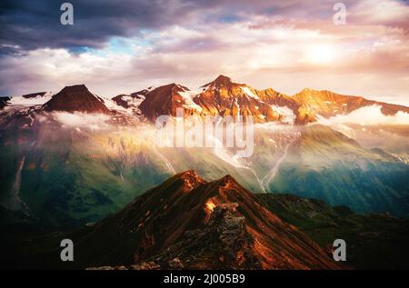 Ein Blick auf die sonnenbeschienenen Hügel in der Dämmerung. Dramatische Abendszene. Lage Ort Großglockner Hochalpenstraße, Österreich. Europa. Klimawandel. Drohne Stockfoto