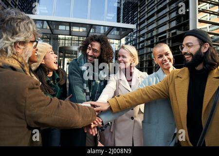 Eine Gruppe lächelnder Geschäftsleute, die sich zusammenschließen, um einen Deal zu schließen Stockfoto