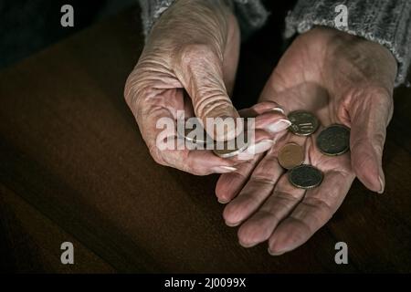 Nahaufnahme der Hände älterer Frauen mit Euromünzen. Rentnerin zählt Geld in ihre Hände Stockfoto