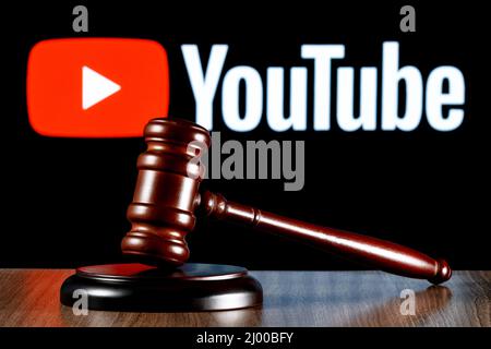 Gavel auf dem Tisch vor dem Hintergrund des Youtube-Logos. Das Konzept des Prozesses. Stockfoto