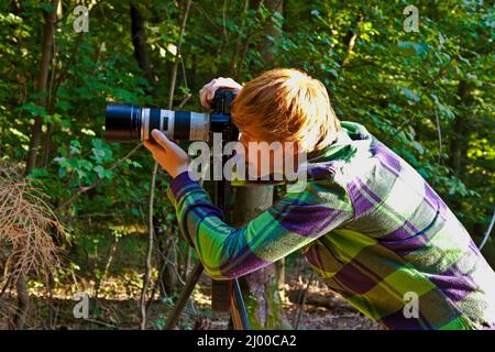 Junge Fotografieren mit tripot der Blätter im Detail Stockfoto