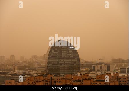 Madrid, Spanien. 15. März 2022. Die Hauptniederlassung der BBVA Bank wird mit Nebel beobachtet, der durch eine große Menge von Staubpartikeln in Suspension aus der Sahara erzeugt wird, was zu einer Abnahme der Luftqualität, Sand in den Straßen, einem rötlichen Himmel und steigenden Temperaturen führt. Die Gemeinde Madrid hat empfohlen, wegen der schlechten Luftqualität die Aktivitäten im Freien zu beschränken. Quelle: Marcos del Mazo/Alamy Live News Stockfoto