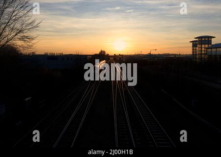 East Midlands Züge der Klasse 222 Merdian Train 222018 auf der midland-Hauptlinie in Nottingham mit Zug und Schienen, die in der untergehenden Sonne glitzern Stockfoto