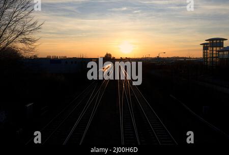 East Midlands Züge der Klasse 222 Merdian Train 222018 auf der midland-Hauptlinie in Nottingham mit Zug und Schienen, die in der untergehenden Sonne glitzern Stockfoto