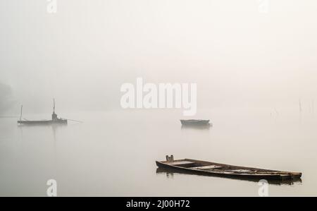 Schöne Aufnahme eines Holzbootes in dem mit dichtem Nebel bedeckten Teich in der Nähe der Stadt Novi Sad, Serbien. Stockfoto