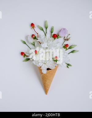 Schöne Blumenstrauß in Eis-Kegel auf weißem Hintergrund. Blumenarrangement, flaches Lay-Styling. Draufsicht. Kreative Stillleben Idee des Frühlings Wallpa Stockfoto