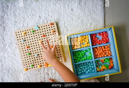 Draufsicht auf die Hand eines Kindes, das ein Lernspiel spielt und Farben sortiert Stockfoto