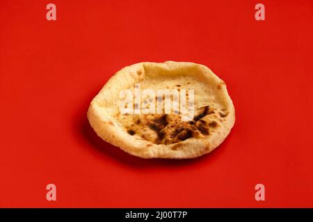 Ägyptisches Brot Aish Baladi. Frisches Brot liegt auf dem roten Tisch Stockfoto