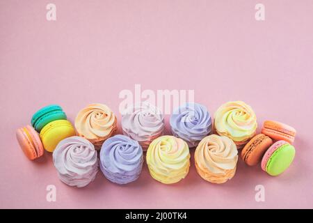 Verschiedene Desserts: Makronen, Sumpfgebiete und Zephyren auf rosa Hintergrund, Nahaufnahme. Traditionelle farbige süße Desserts für den Urlaub, Kopie SPAC Stockfoto