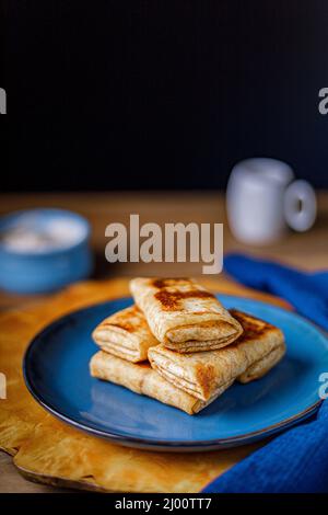 Pfannkuchen mit Quark-Füllung auf einem blauen Teller. Nahaufnahme. Stockfoto
