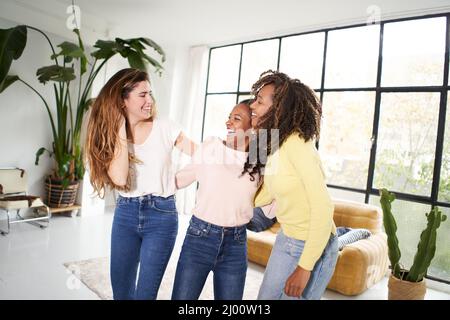 Party zu Hause verschiedene weibliche Freunde feiern Wohnzimmer drinnen. Multirassische fröhliche Frauen tanzen und feiern die Lebensfreude fröhlich Stockfoto