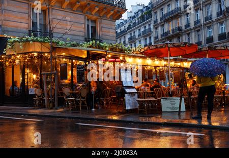 Paris, Frankreich-März 13 , 2022 : das traditionelle französische Café Kassette in regnerischer Nacht . Es befindet sich im Viertel Montparnasse in Paris, Frankreich. Stockfoto