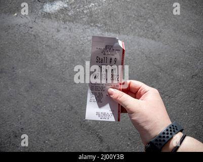 Seattle, WA USA - ca. März 2022: Ansicht einer kaukasischen weiblichen Hand, die einen Parkschein hält, um auf einem Armaturenbrett in der Innenstadt von Seattle zu platzieren Stockfoto